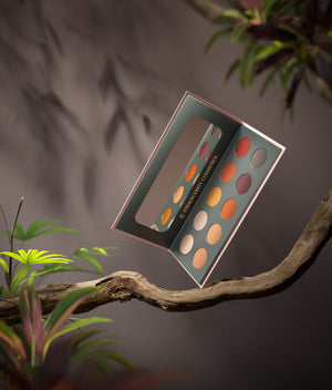 Inside of the red panda palette revealing all ten eyeshadow shades. the palette is suspended on a branch surrounded by leaves and foliage